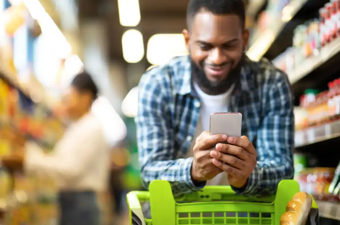 Man saving money with money saving app at grocery store