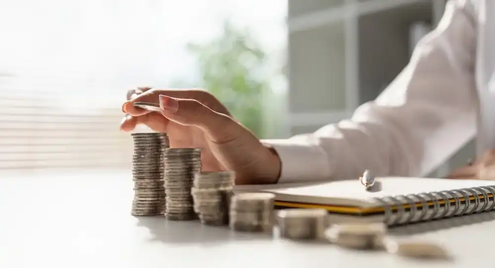 Someone stacking coins next to a notebook