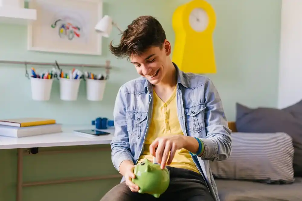 A student putting money in their piggy bank for their college fund