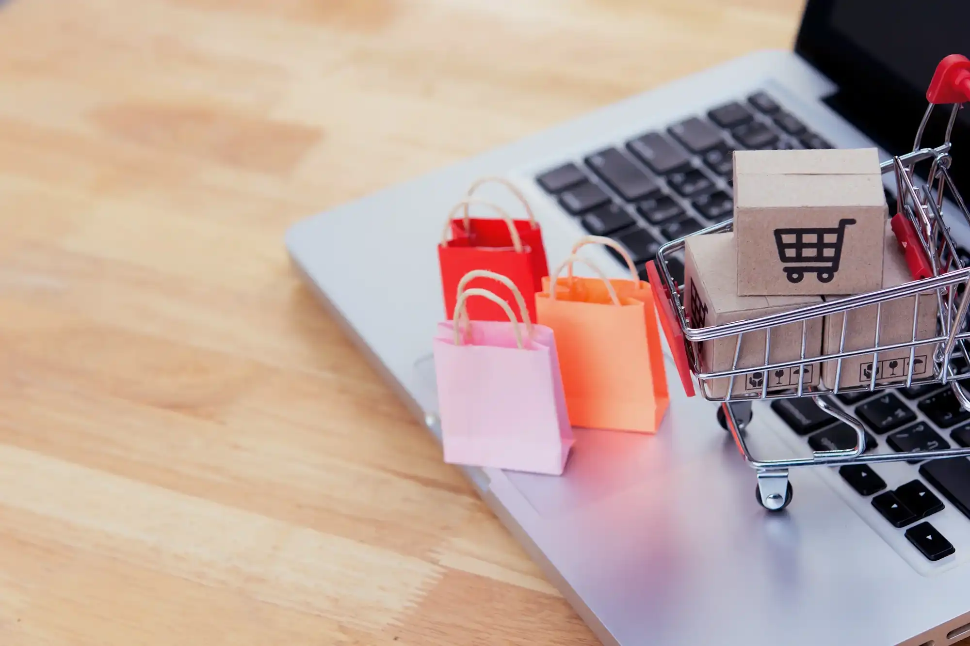 Mini shopping bags and shopping cart on top of a laptop