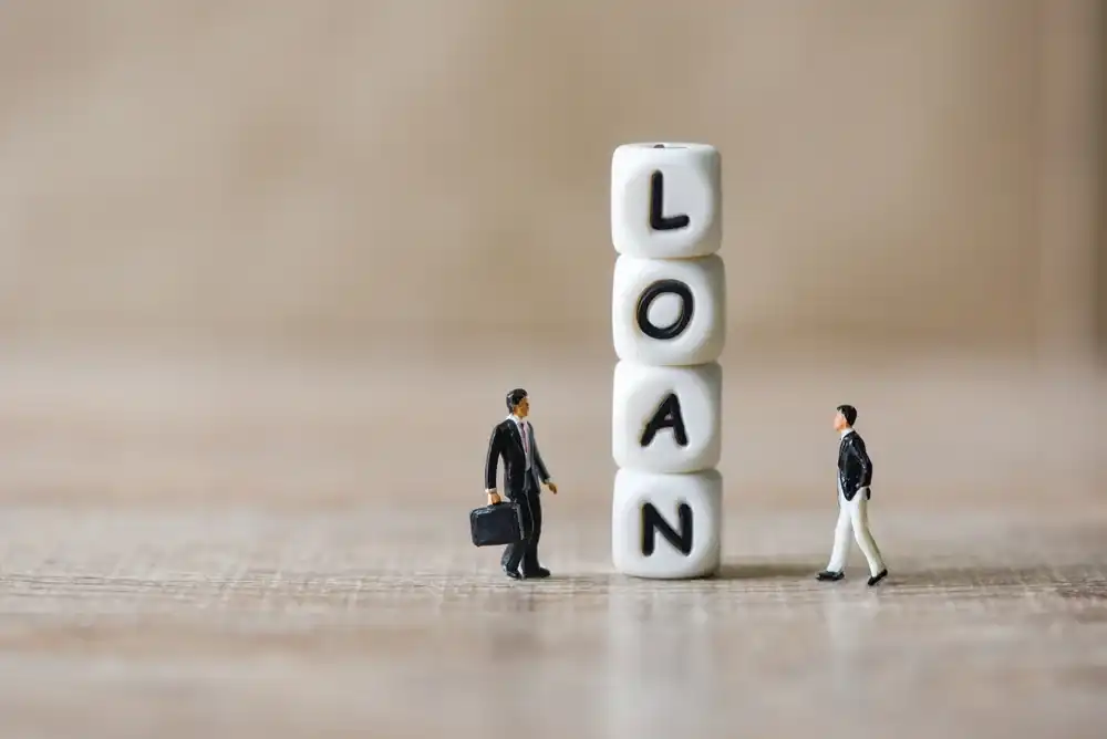 A stack of blocks that spell "Loan" next to two figures