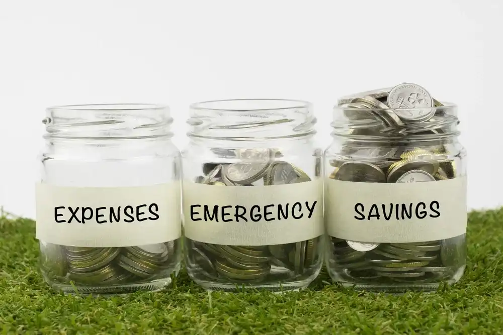 Three jars labeled "Expenses, Emergency, Savings" full of change