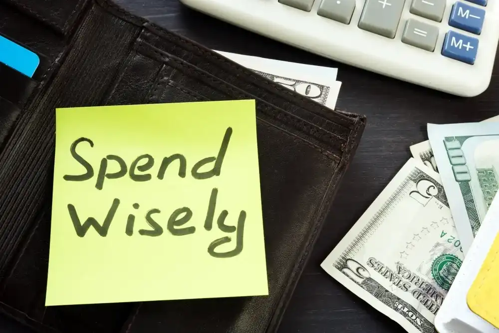 A post-it note that reads "Spend Wisely" attached to a wallet