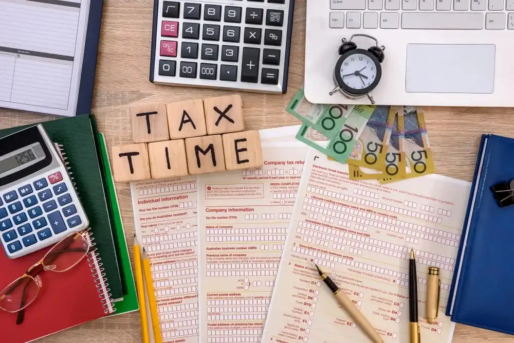 Blocks that spell out "Tax Time" atop a desk with taxes on them